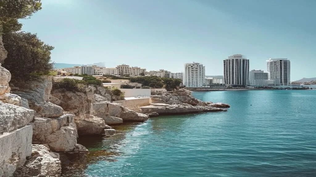 A calm Paphos coastline on one side and a modern Limassol skyline on the other, sunny day